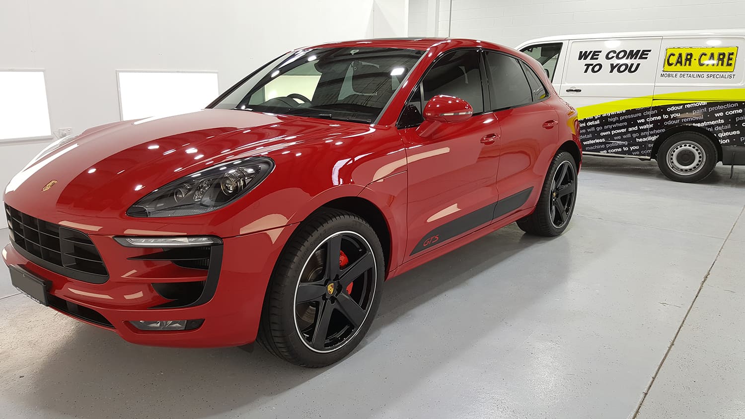 A freshly cleaned Red Porsche Macan S, that has had a full car detailing service on it, in a showroom